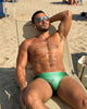 Man reclining on a beach lounger in a green Seaman Swim men's swim brief
